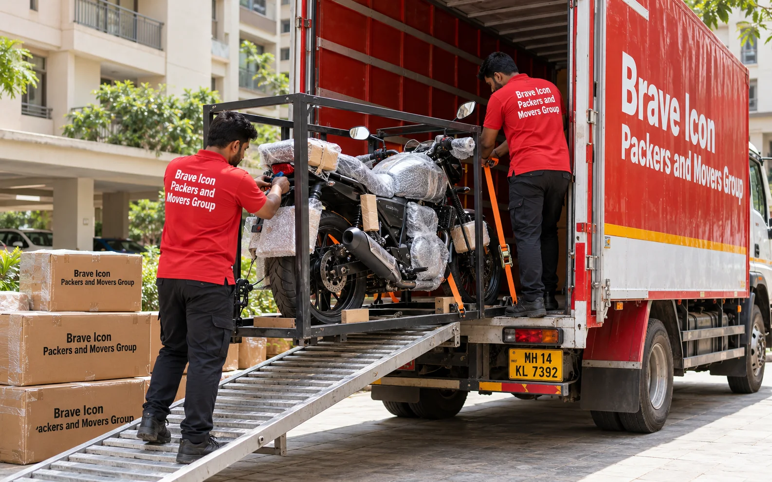 Movers secure a protected motorcycle in a transport frame inside a red-and-white carrier truck.